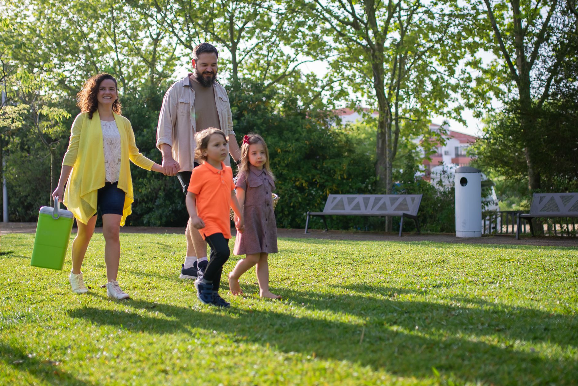 Familie mit zwei Kindern beim Spaziergang im Park an einem sonnigen Tag