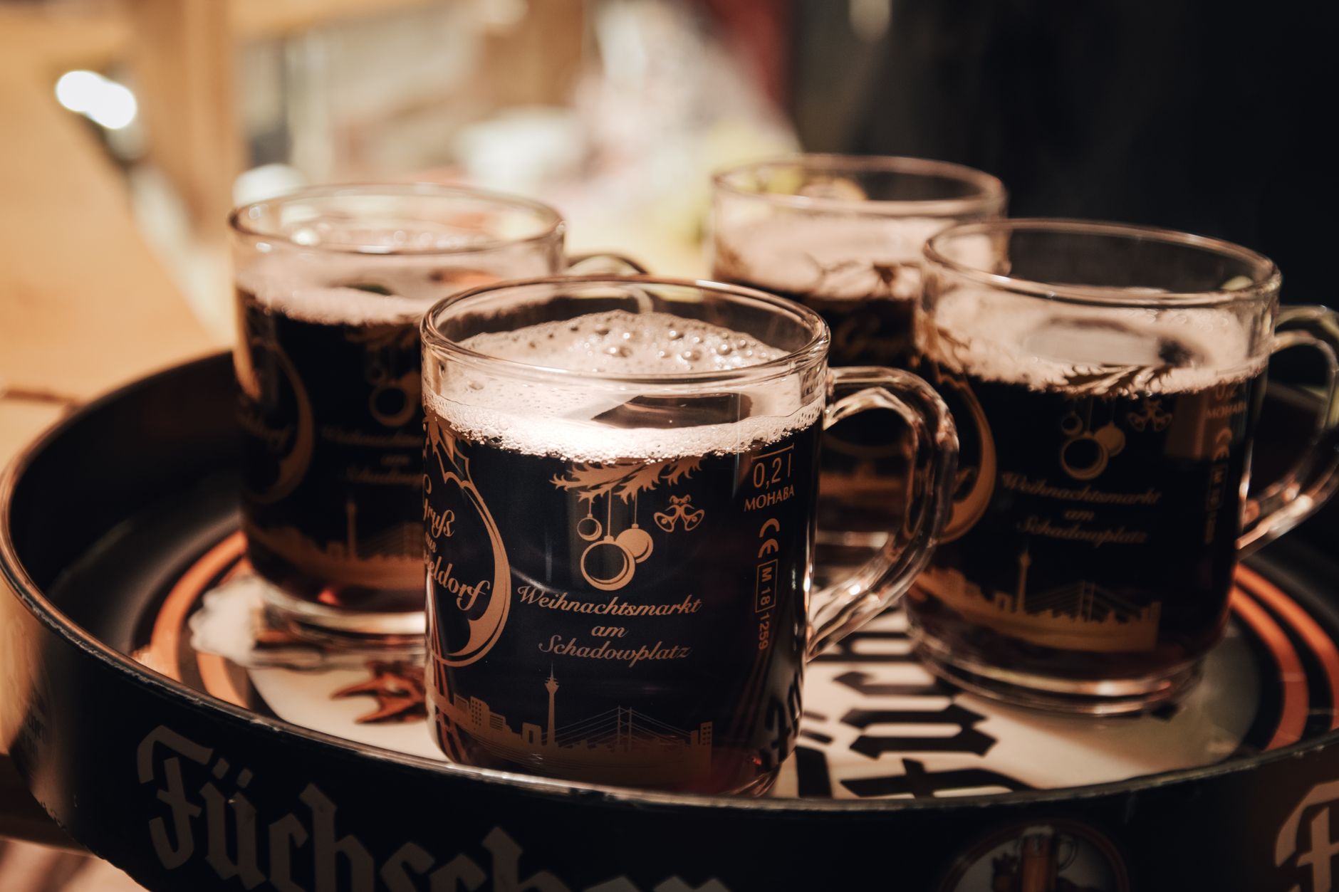 Weihnachtsmarkt in NRW – Gläser mit dampfendem Glühwein auf einem Tablett