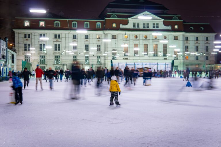 Schlittschuhlaufen in Köln: Eishallen, Eisbahn am Heumarkt und Eisstockschießen 2026/27 Schlittschuhlaufen Köln – Menschen auf einer beleuchteten Open-Air-Eisbahn am Abend