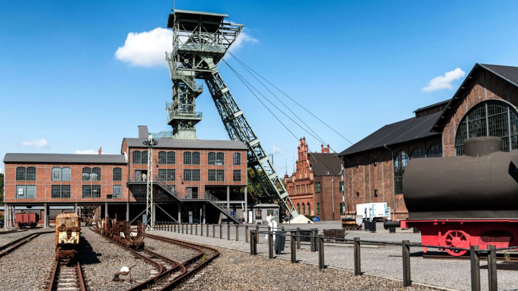 Fördergerüst und Gebäude der Zeche Zollern in Dortmund mit alten Grubenwagen auf Gleisen