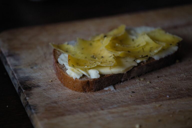 Halve Hahn: Was hinter dem kölschen Käsebrötchen steckt Halve Hahn – Scheibe dunkles Brot mit Butter und Käse auf einem Holzbrett