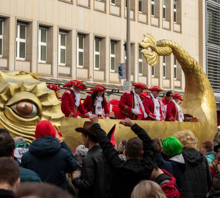 Karneval 2027: alle Termine in NRW vom 11.11. bis Aschermittwoch Karneval 2027 – Festwagen mit goldenem Fisch und Karnevalisten in roten Uniformen im Kölner Zug