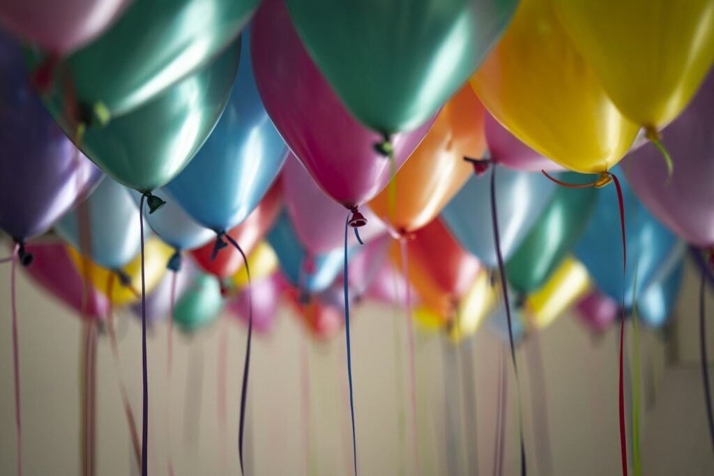 Bunte Luftballons mit Bändern an der Decke bei einer Geburtstagsfeier