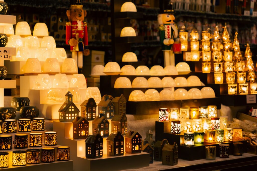 Marktstand mit beleuchteten Windlichtern, Porzellanhäuschen und Nussknackern auf einem Weihnachtsmarkt (Symbolbild)