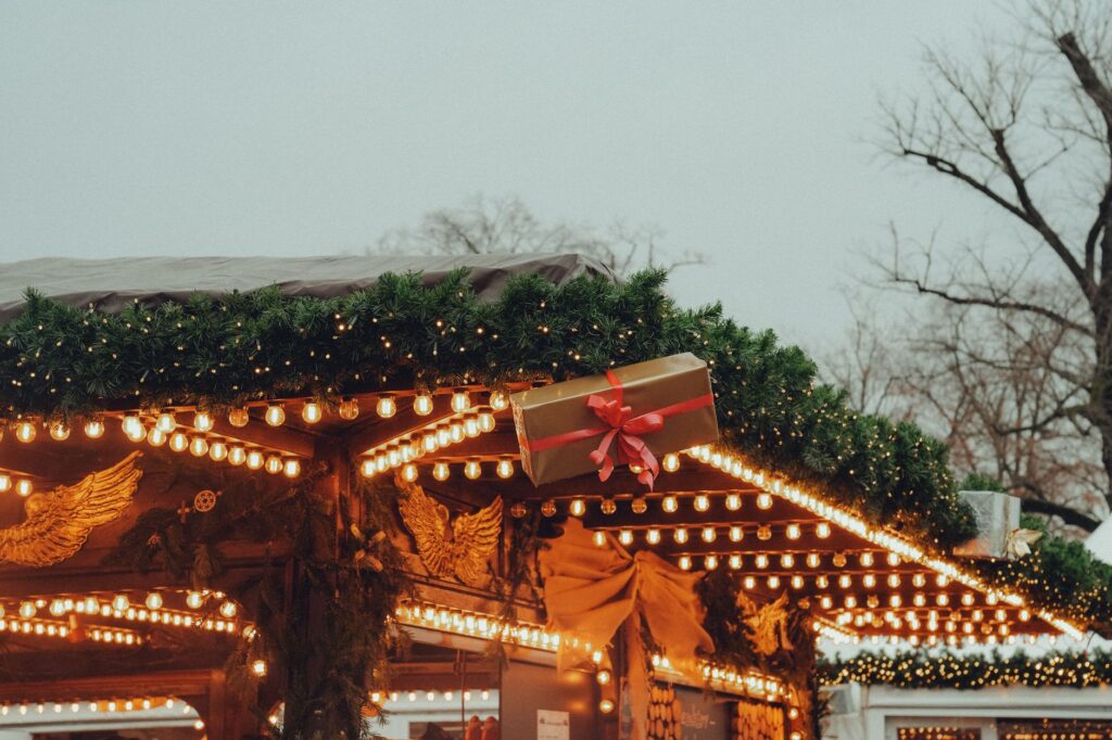 Beleuchtete Weihnachtsmarkthütte mit Tannengirlande und Lichterketten als Symbolbild für die Märkte in Leverkusen