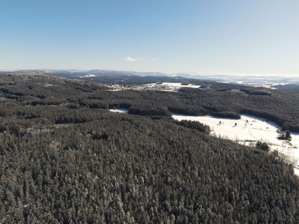 Winterliche Mittelgebirgslandschaft mit verschneiten Fichtenwäldern aus der Luft