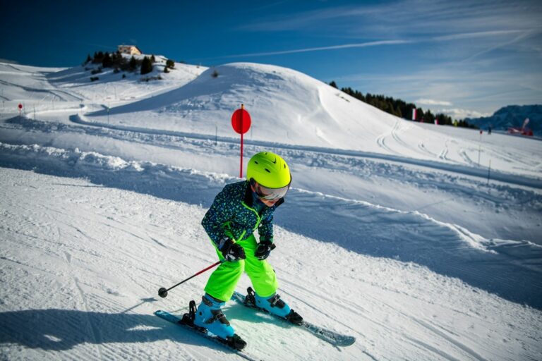 Winterberg mit Kindern – Kind mit Helm beim Skifahren auf einer Skipiste